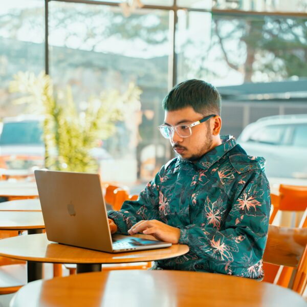 Young Man in a Floral Jacket Working on a Laptop