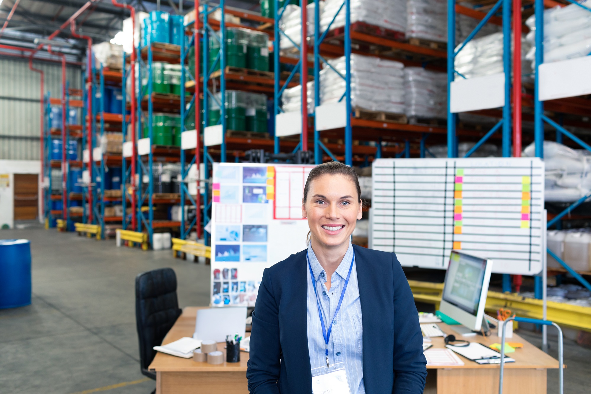 Reverse Logistics Services 5 Smiling businesswoman standing in warehouse office, surrounded by inventory shelves