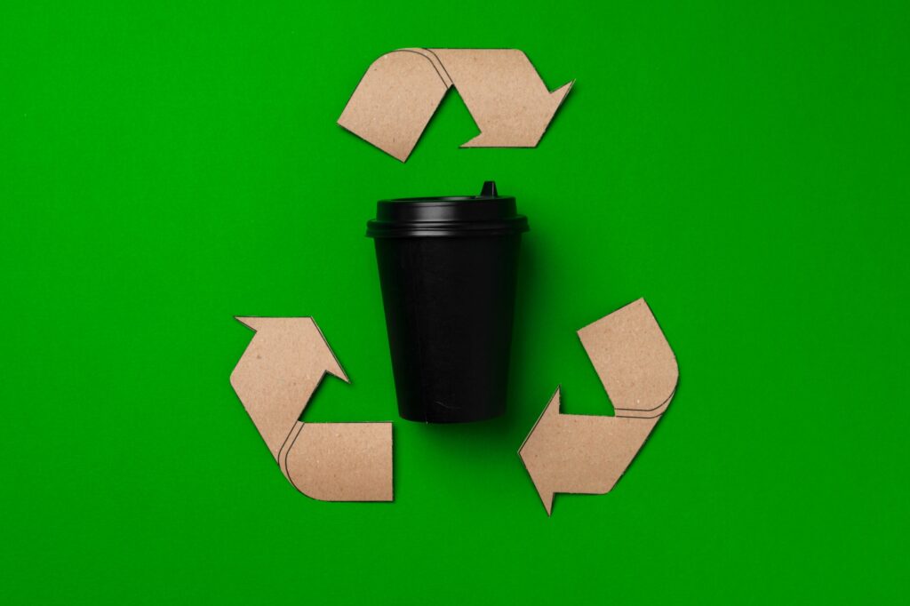 Returns Disposal Services 2 Disposable coffee cup and recycling sign on green background